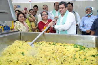 Shri Mukul Hasteer and Smt Reena Sharma participate in cooking mid-day meals for children.